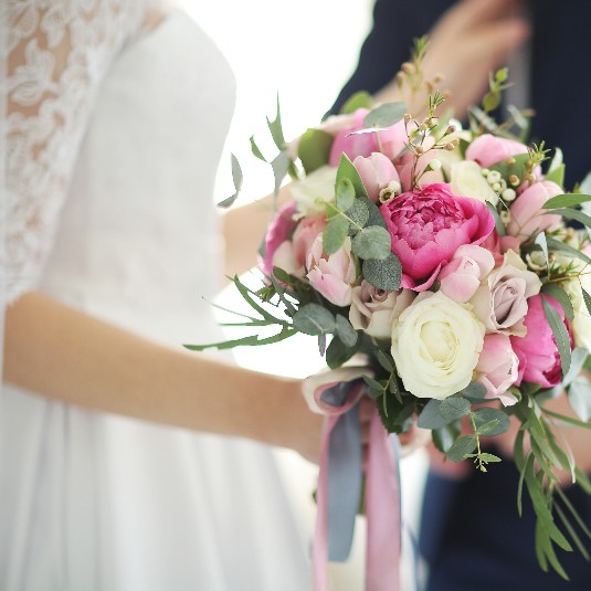 A bride and groom holding their wedding bouquet.