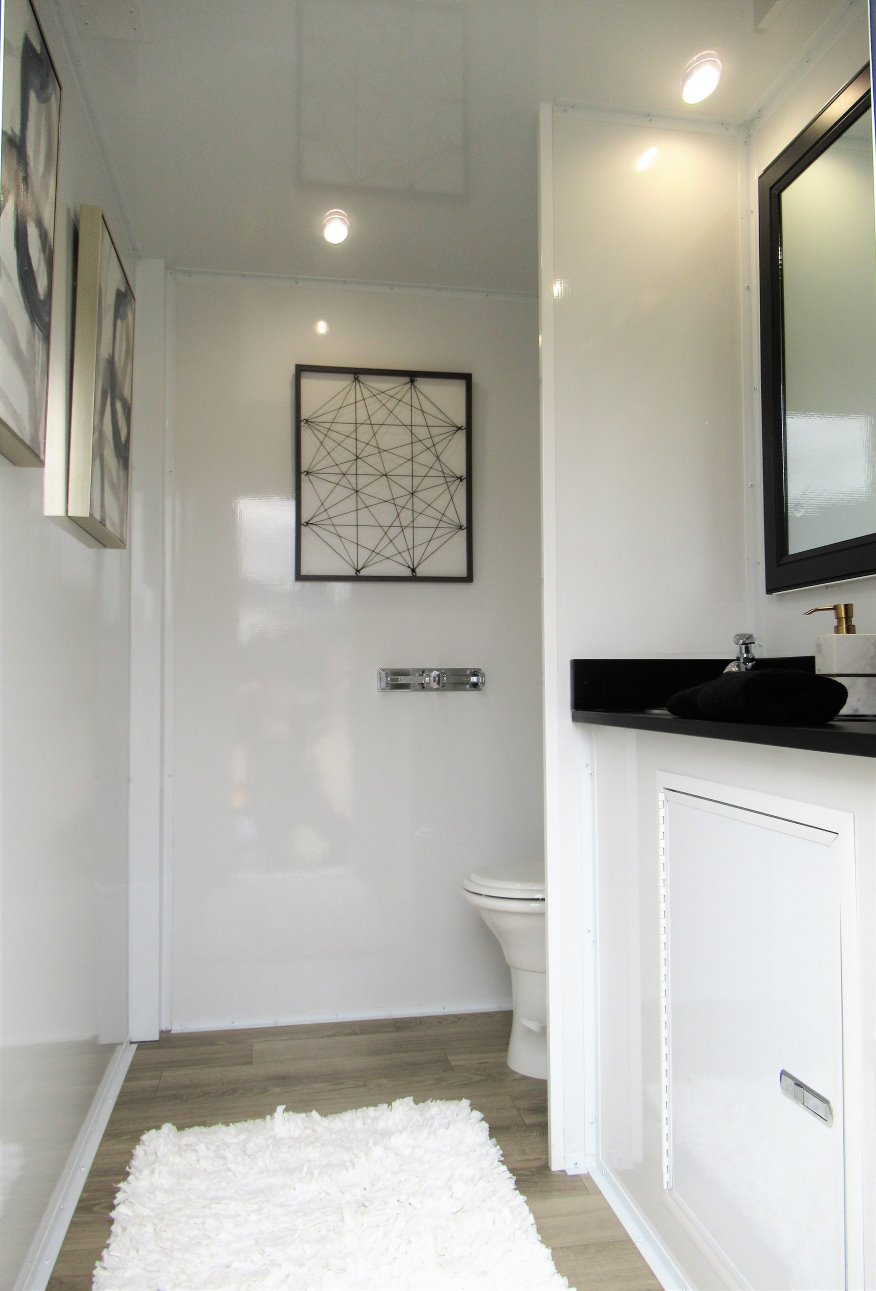 A bathroom with white walls and black counter tops.