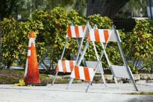 Orange traffic cone and striped barricades at a roadside construction site