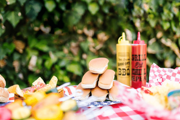 Ketchup and mustard on a patriotic picnic table at a cookout.