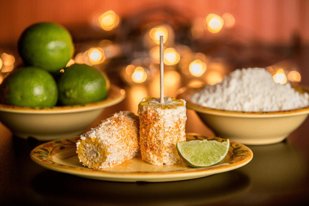Mexican street corn (elote) with lime and cotija on a festive table.