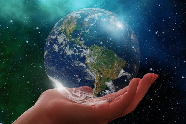 Hand holding a globe with the Americas visible against a starry background.