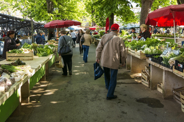Shoppers walking through an outdoor farmers market.