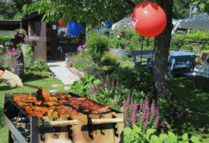 Backyard Labor Day cookout with balloons, grill, and garden seating.