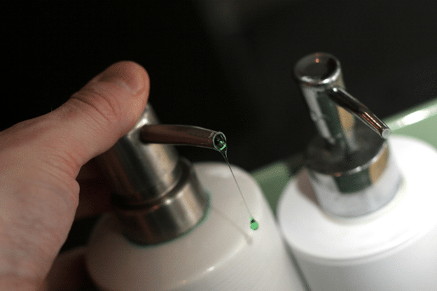 Hand dispensing liquid soap from a pump—portable restroom touchpoint hygiene.