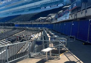Stadium concourse lined with blue screened fence panels during seating renovations.
