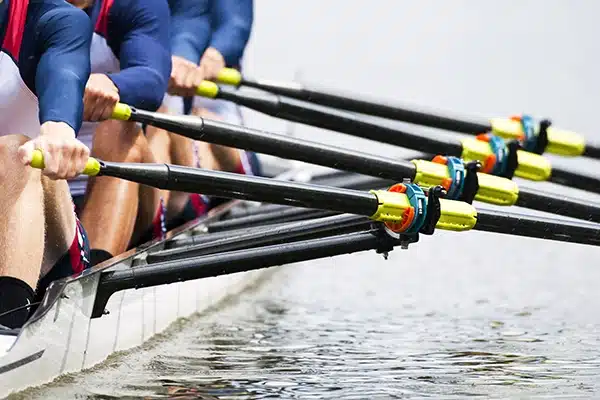 Rowing crew pulling oars in sync during a regatta—close-up on oar blades skimming the water.