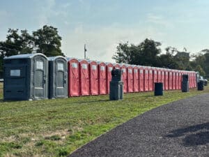 Long row of portable restrooms with handwash stations set up for an outdoor event.