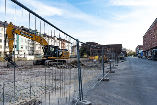 Chain-link panel fencing surrounding an urban construction site with excavator.